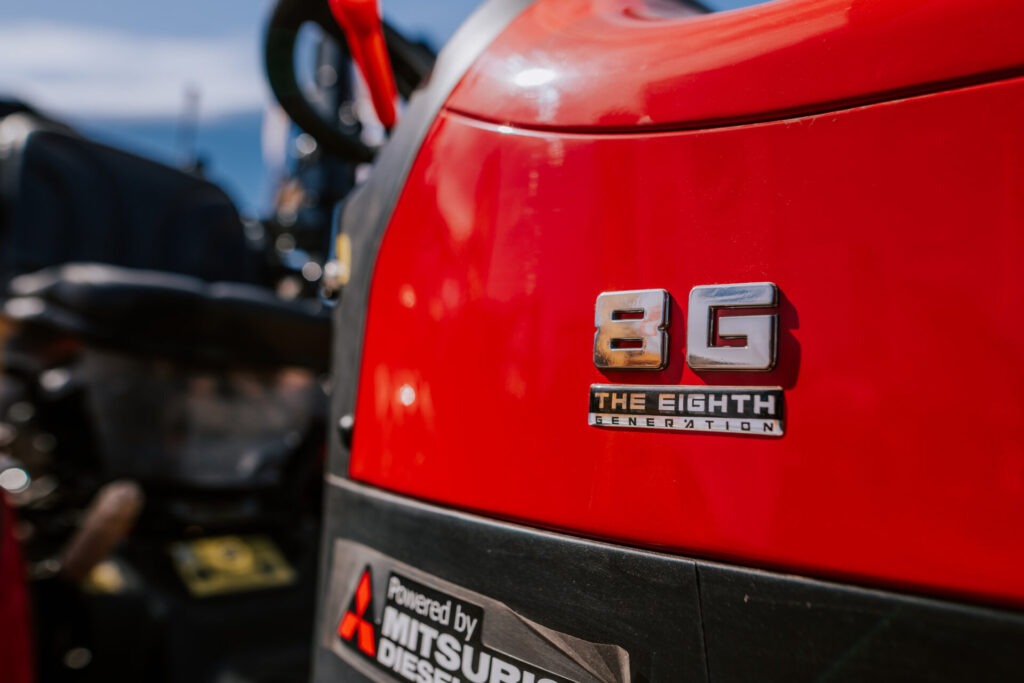 Lähivõtte punasest sõidukist, millel on näha kroomitud 8G THE EIGHTH GENERATION märk ja kleebis, millel on kirjas Powered by Mitsubishi Diesel, hägune taust. Foto on tehtud Maamessil 2026 toimunud Kone Agro üritusel.